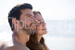 Side view of thoughtful couple sitting at beach