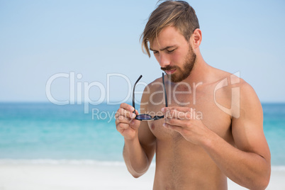 Shirtless man holding sunglasses