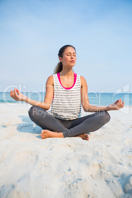 Full length of woman with eyes closed meditating at beach