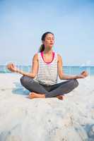 Full length of woman with eyes closed meditating at beach