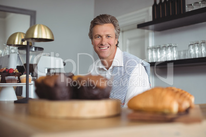 Portrait of smiling waiter standing at bar counter