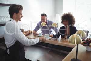 Waiter serving coffee to costumer at counter