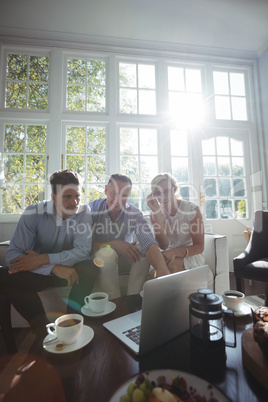 Friends discussing over laptop