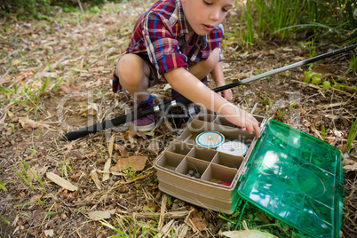 Boy with fishing rod searching in the box
