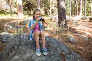 Girl looking through binoculars in the forest