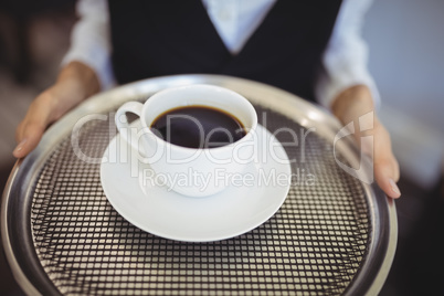 Mid-section of waitress holding tray with black coffee
