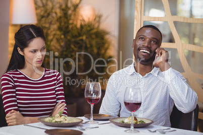 Man ignoring bored woman while talking on mobile phone