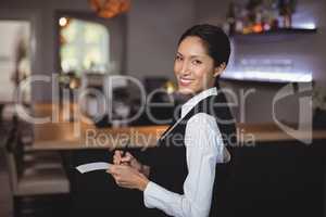 Smiling waitress writing order on notepad