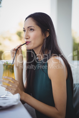 Woman having cocktail while relaxing on sofa