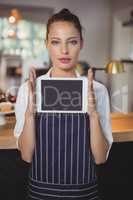 Portrait of waitress holding digital tablet at counter