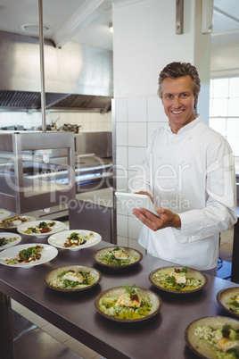 Portrait of male chef using digital tablet at order station