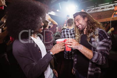 Cheerful friends toasting drinks at music concert