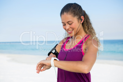 Happy woman using smart watch at beach
