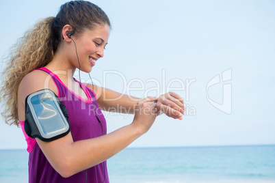 Smiling young woman using smart watch at beach