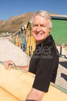 Man carrying surfboard while standing against beach huts