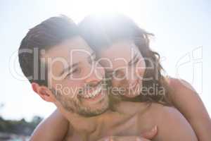 Happy shirtless couple embracing at beach