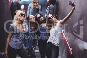 Female friends taking selfie while standing on steps