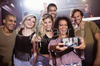Cheerful friends talking selfie at nightclub