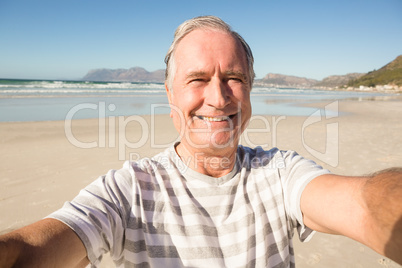 Portrait of smiling senior man standing at beach