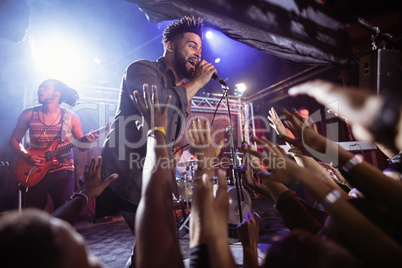 Male singer performing on stage by crowd at nightclub