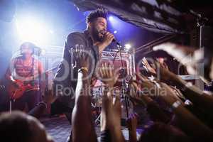 Male singer performing on stage by crowd at nightclub
