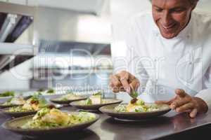 Male chef examining appetizer plates at order station
