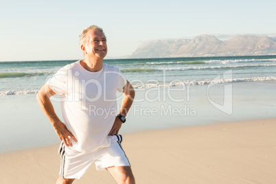 Smiling senior man exercising while standing on sand