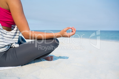 Low section of young woman meditating at beach