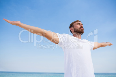 Man with arms outstretched exercising at beach