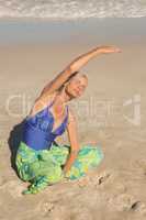 High bangle view of woman exercising while sitting on sand