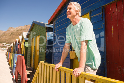 Happy man looking away while standing at beach hut