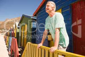 Happy man looking away while standing at beach hut