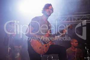 Thoughtful guitarist perfoming with guitar during music festival