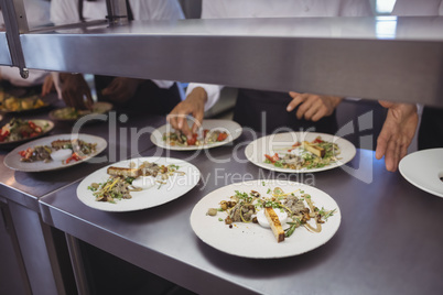 Team of chefs garnishing meal on counter