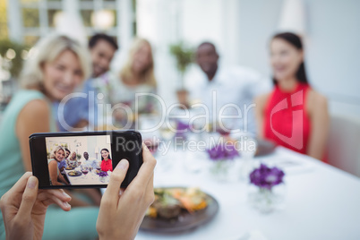 Woman photographing of friends sitting at table