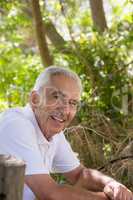 Portrait of smiling senior man leaning on wooden fence