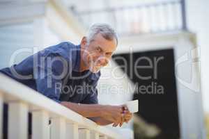 Portrait of mature man holding a coffee cup in balcony