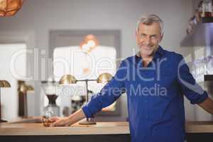 Portrait of mature man standing at counter