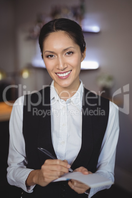 Smiling waitress writing order on notepad