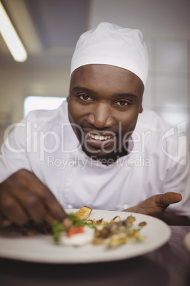 Portrait of chef garnishing meal on counter in commercial kitchen