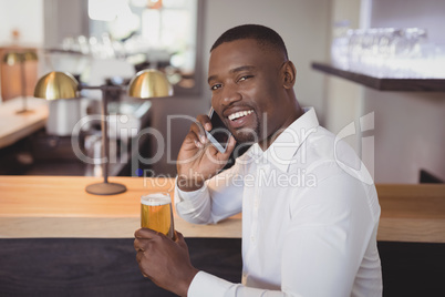 Man talking on mobile phone while having beer