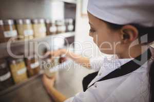 Female chef selecting a spice jar in the commercial kitchen