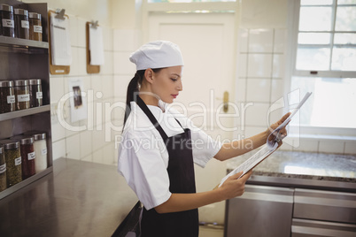 Female chef looking at clipboard in the commercial kitchen