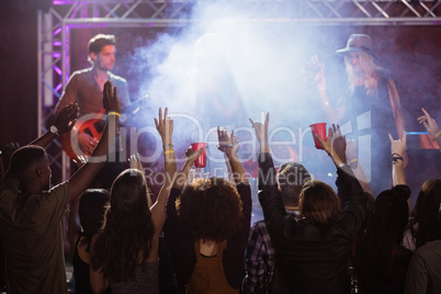 Fans with arms raised enjoying music concert