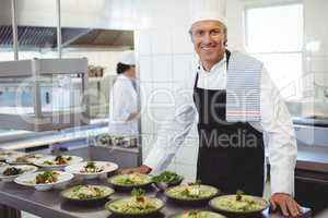 Portrait of happy chef with appetizer plates at order station