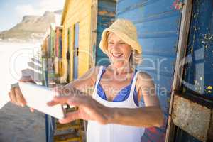 Smiling woman holding mobile phone while standing against wall