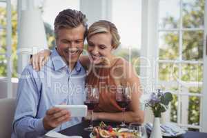 Couple enjoying using mobile phone in restaurant
