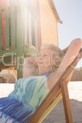 Low angle view of woman relaxing on chair against hut