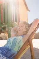 Low angle view of woman relaxing on chair against hut