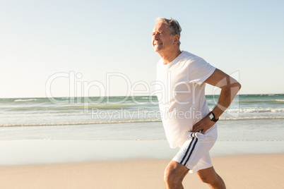 Senior man running on shore against clear sky